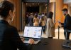 Organizadora de eventos revisando ventas online mientras el equipo valida entradas en un auditorio