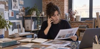 Una profesional revisa una propuesta y habla por teléfono en una oficina pequeña.